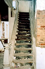 <two photo series> Incompatible Treatment of Stairhall and Stairway. Major alterations to distinctive interior features will also fail to meet the Standards for Rehabilitation. As part of the rehabilitation, the historic stairhall has been eliminated (shown) and the open stairway enclosed (shown), resulting in the loss of the spatial context and removal of the decorative newel post and stair railing. Photos: NPS files