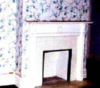 This shows a bedroom, prior to rehabiltiation, with its existing floral wallpaper.