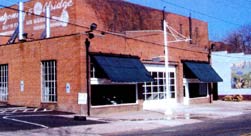 The compatible new use as company offices for this historic garage successfully utilizes the large volume of the former auto service area as well as the existing office partitions. The later, non-significant garage door has been replaced with a new insulated overhead door with glass panels. A functional garage door was not required in order to maintain the historic character of the building.  A fixed partition made of wood or metal that resembled a traditional garage door would also have been appropriate.