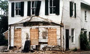 This two-story frame house, c. 1870, is severely deteriorated, but is still able to convey its historical significance within the district prior to rehabilitation. Photos: NPS files.