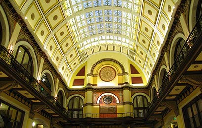 Three-story interior space flanked by arcades and topped by an arched coffered ceiling with a stained glass skylight.