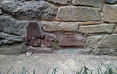Close-up view of a stone foundation with some deteriorated stones. 