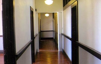 Historic building corridor lit by partially glazed walls and doors and a skylight.