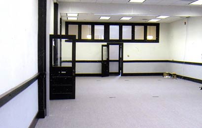 Room with partially glazed walls and doors that allow light out into the corridor.