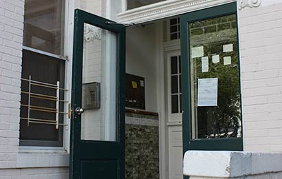 Open door leading into a vestibule of a white brick building.