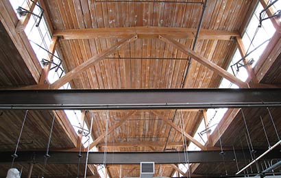 Clerestory windows above roof beams and trusses in an industrial building.