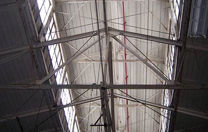Interior of an industrial building, focusing on the roof monitor with windows and the roof trusses.