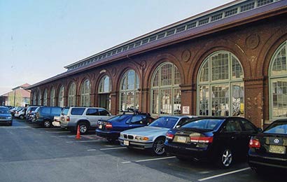 One-story red brick building with large, arched, multi-light windows and a monitor with windows on the roof.