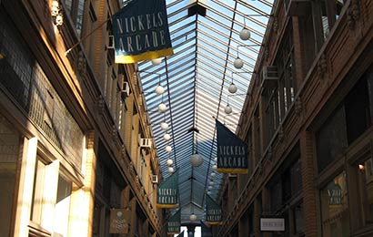 Two-story arcade with banners saying “Nickels Arcade” and covered with a glass skylight as a roof.