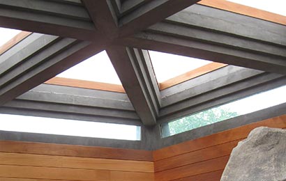 Skylight constructed as a design feature with wood framing inside a Frank Lloyd Wright house, with a large boulder on the right.