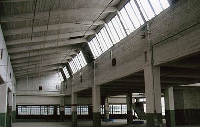 Interior of an industrial building with exposed wood structure and clerestory windows, before rehabilitation.