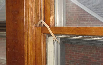 Close-up view of a broken sash cord on a wood window.