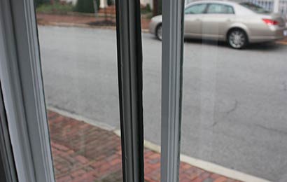 Close-up of a mullion of an interior storm window and a window, showing that they match.