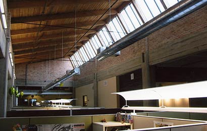 Interior of an industrial building with exposed wood structure and clerestory windows, after rehabilitation into offices.