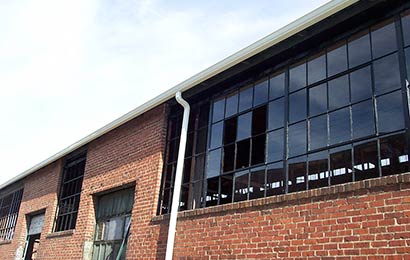 Brick industrial building with steel multi-light windows undergoing repair.
