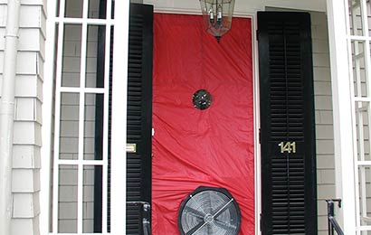 Front door of a house covered by plastic and with a fan in the lower part of the door, in preparation for a blower door test.