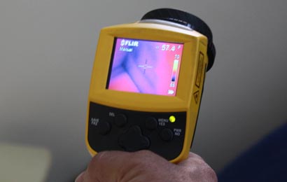 Hand holding a piece of equipment used to test the amount of heat transferred through a wall.