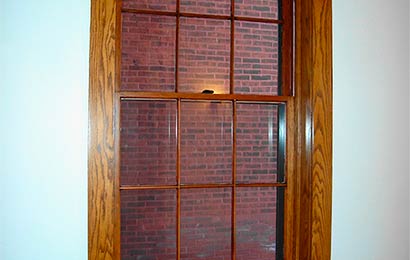 Interior view of a wood six-over-six window surrounded by wood trim.