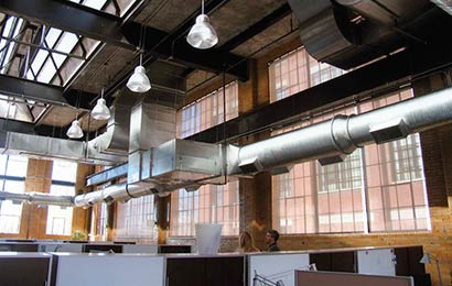 Interior of an industrial building converted to an office, which is lit by a roof monitor and large, multi-light windows.