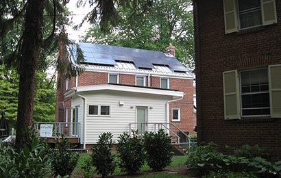 Solar panels covering the roof of a two-story brick house.