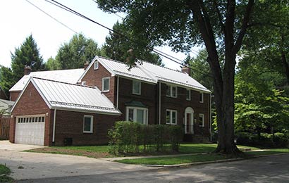 Red brick house with a white standing-seam metal roof.
