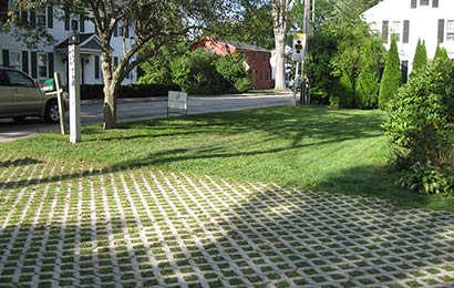Driveway constructed of pavers with grass growing between them, with a grass lawn in the background. 