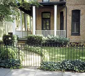 This is an image of an urban house with a visually distinctive front yard which includes the iron fence along the sidewalk, the curved walk leading to the porch, and the various plantings. Photo: NPS files.