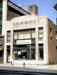 This is an image of a modest commercial building with a  three-part shape, consising of a large center bay with two flanking narrow bays and an upward projecting parapet. Photo: NPS files.