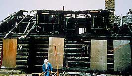 This is an image of architect, David Wark, seen against the ruins of the West log house in Summer, 1991. Photo: Courtesy, Fletcher Farr Ayotte (FFA).