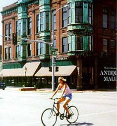 This is an image of the Galesburg Antiques Mall Company, Seminary Street Historic Commercial District, Galesburg, Illinois. A girl on a bicycle is in the foreground. Photo: Jay Matson.