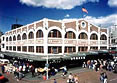 These are side by side images of Pike Place Historical Market in Seattle, Washington. One shows the market during daytime; the other at night with a neon sign that says 'Public Market Center.' Photos: Courtesy, Pike Place Preservation and Development Authority.