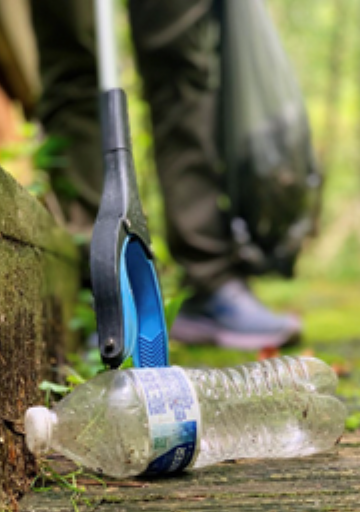 ground-level view of a person using trash grabbers to pick up a plastic water bottle