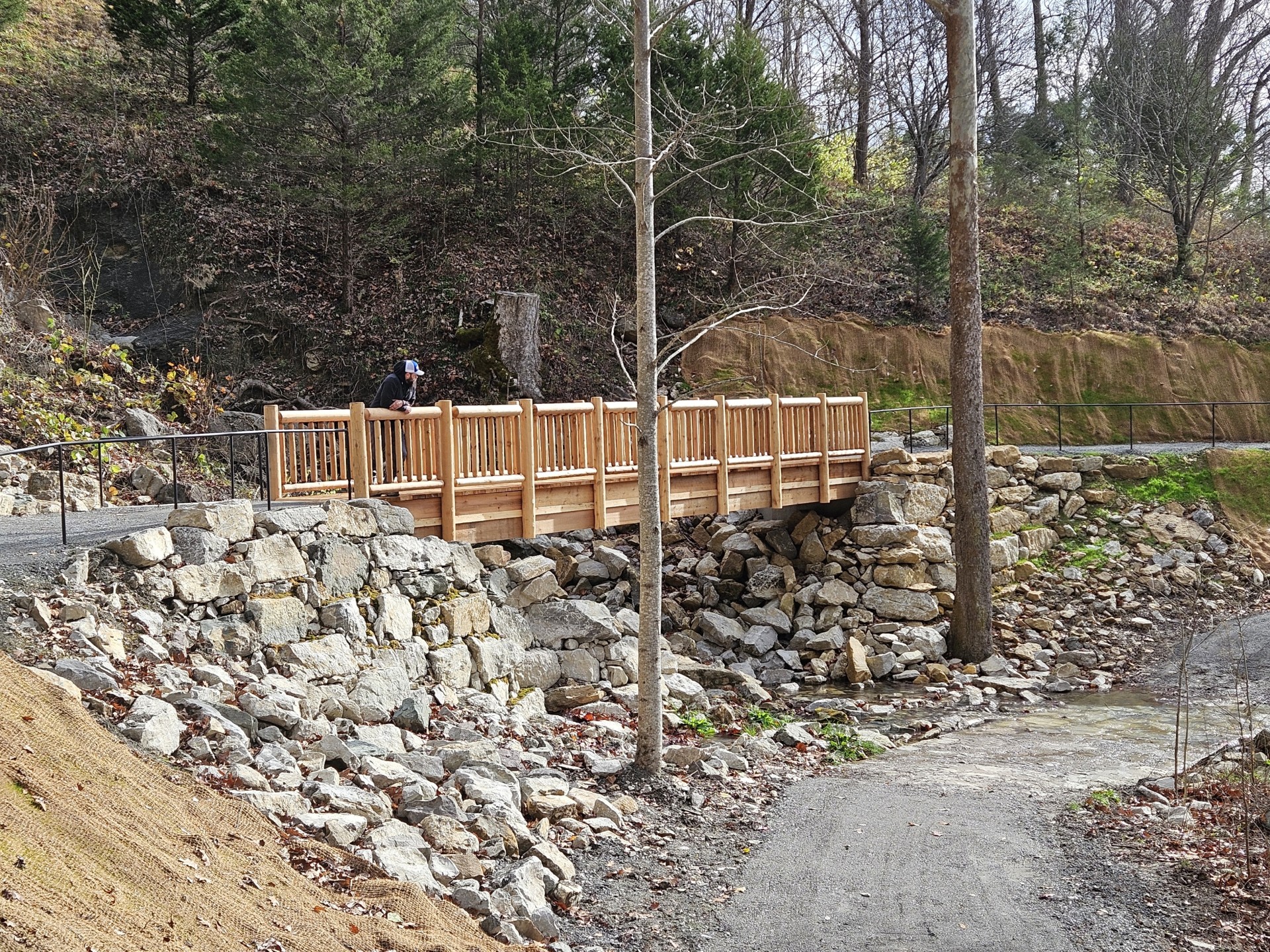 Wooden Bridge with metal handrails over Gap Creek with a person standing on bridge.
