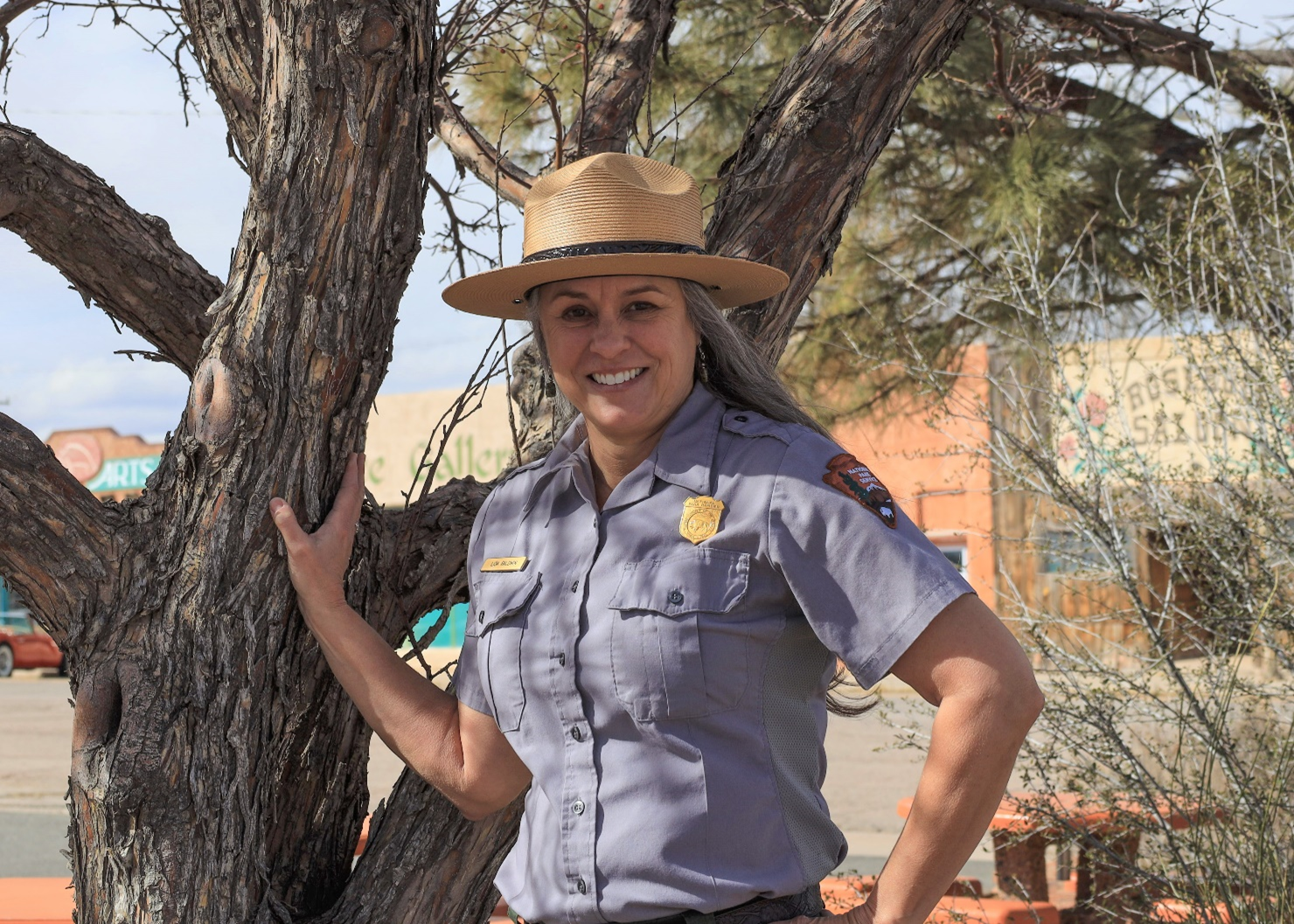 Lisa Baldwin A woman in National Park Service uniform and flat hat stands outside and smiles