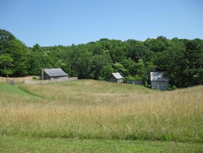 3 historic buildings in a field with trees