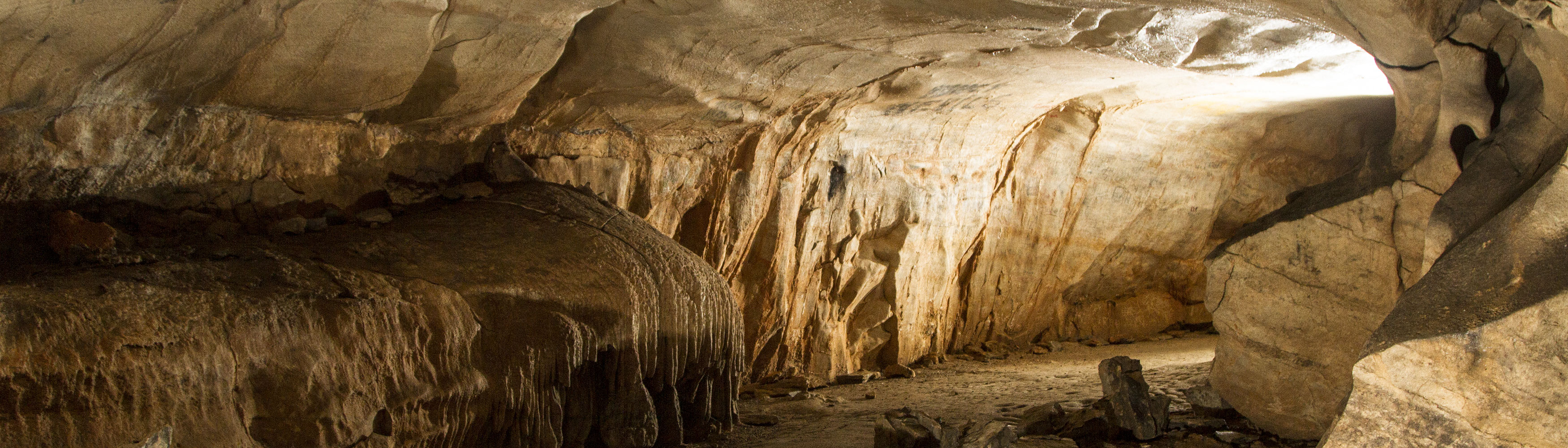 A dark cave system showing light coming from a passageway.