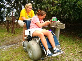 two volunteers work to paint a trail sign