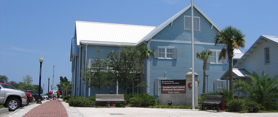 Cumberland Island Mainland Visitor Center Two story blue building along brick walkways, with American flag flying