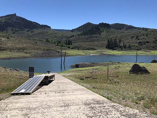nearly dry cement boat ramp amid mountain scenery