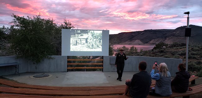 Ranger presenting an amphitheater program with a colorful sunset in the background