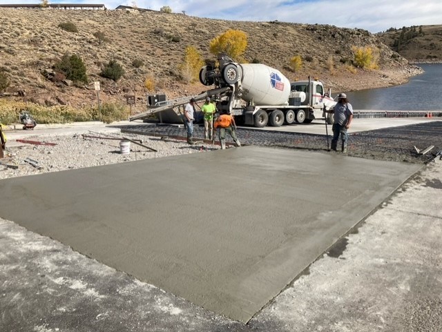 Workers repair a concrete boat ramp next to a reservoir