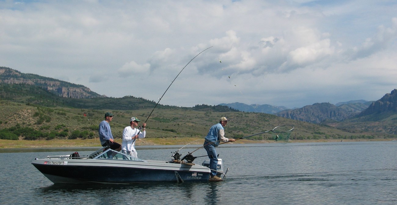 Three people in a motorboat on a lake fishing off the back