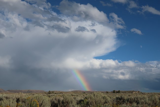 A rainbow over a plateau with storm clouds