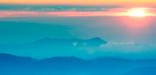 Image of beautiful sunrise over blue misty mountains.
