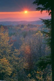 Purple and orange sunset over a forested valley.
