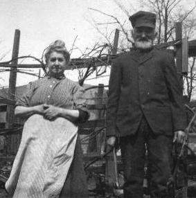 Black and white photo Conrad and Louise Botzum, later in life, with a barn in the background.
