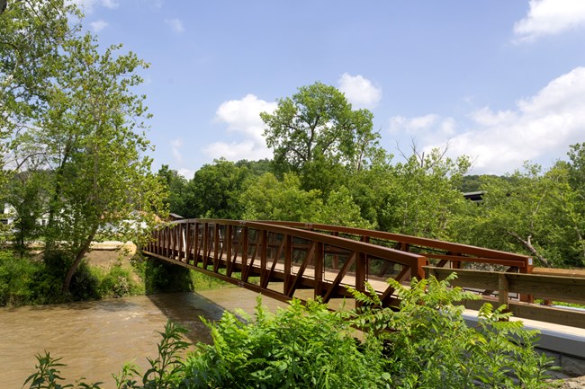 A brown pedestrian bridge over a river.