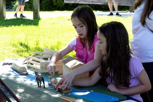 Two girls playing with a canal boat model.