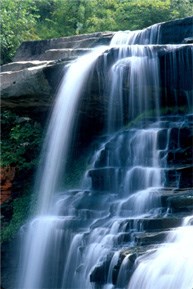 Close-up of a rocky waterfall; the water spills off an upper ledge and cascades down lower step-like edges of the rock.