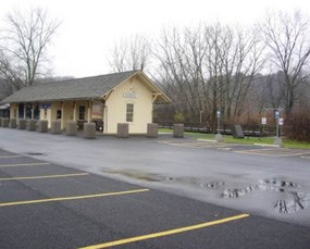 A paved parking area next to a yellow train station.